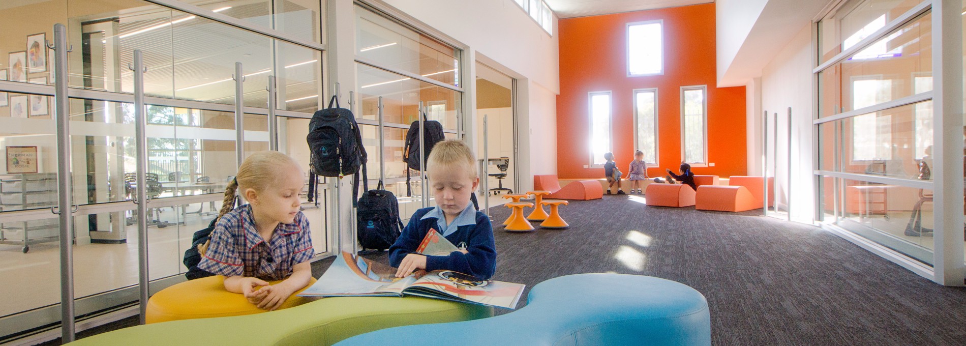 Two Children Reading on Blue and Green Ottomans in a Classroom